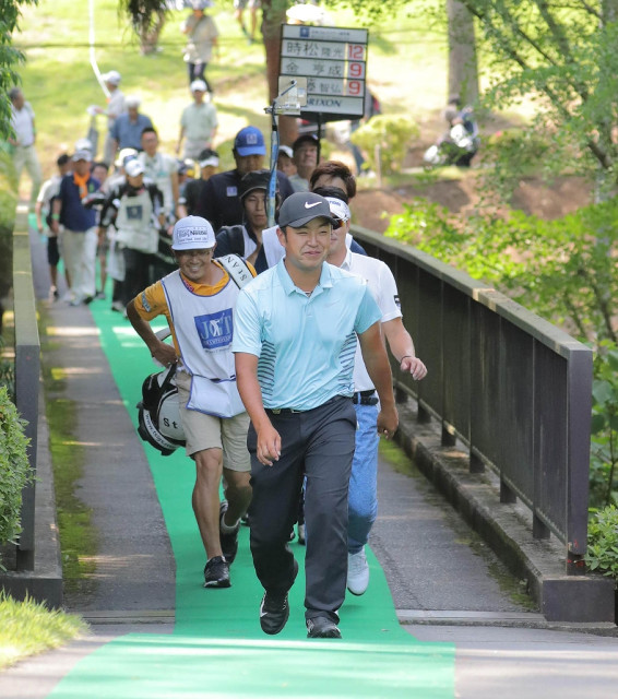 １４番から１５番に向かう橋を笑顔で渡る時松隆光（手前）。単独首位に立つ（カメラ・堺　恒志）