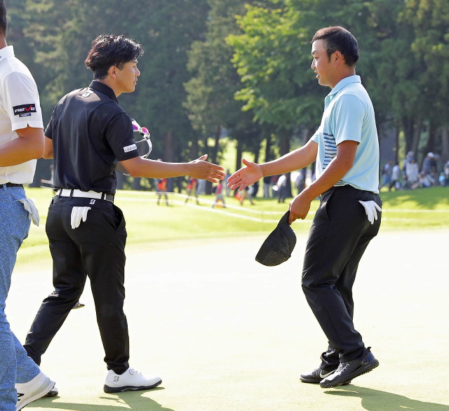 通算１２アンダーで単独首位に立った時松（右）はホールアウト後、３打差２位タイの近藤と握手