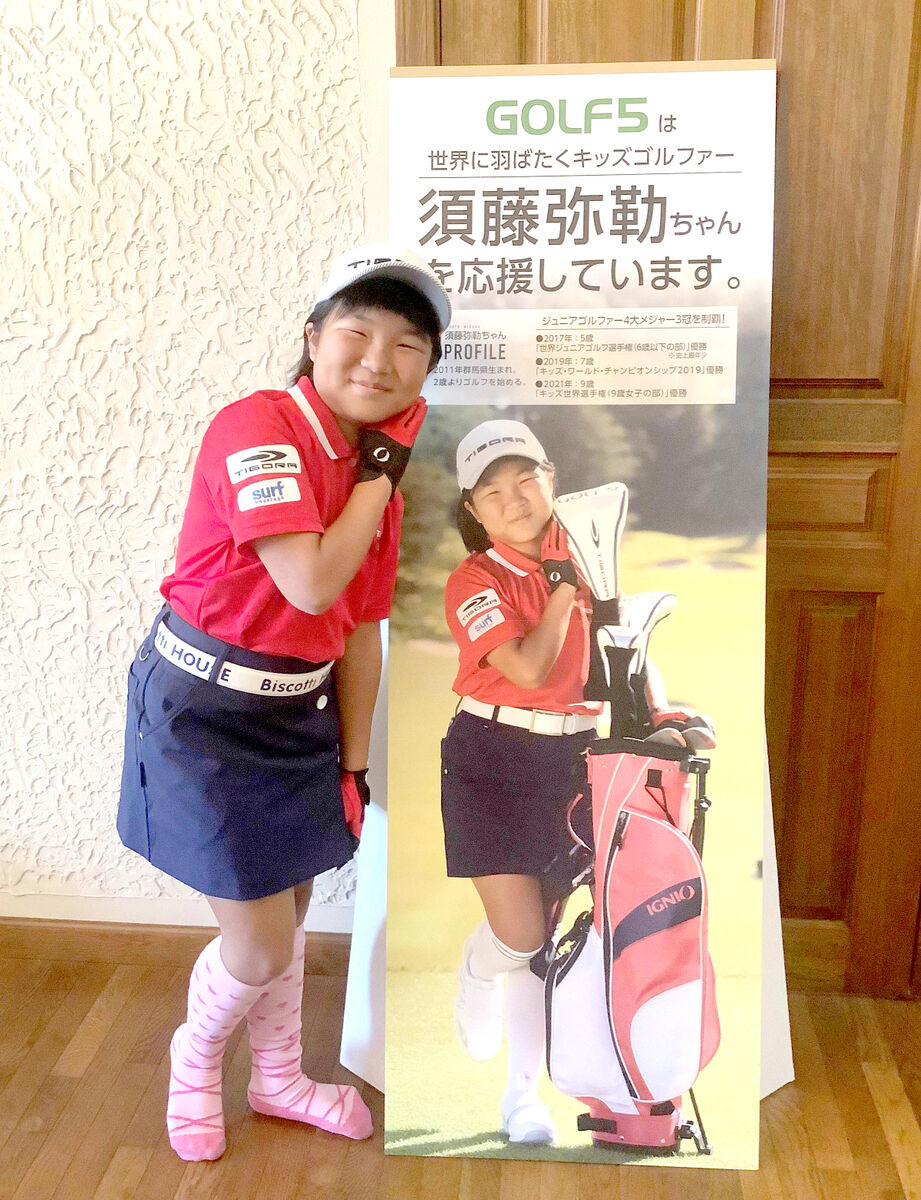 全国のゴルフ５で展示される自身のパネルと「２ショット」で笑顔を見せる須藤弥勒（家族提供）