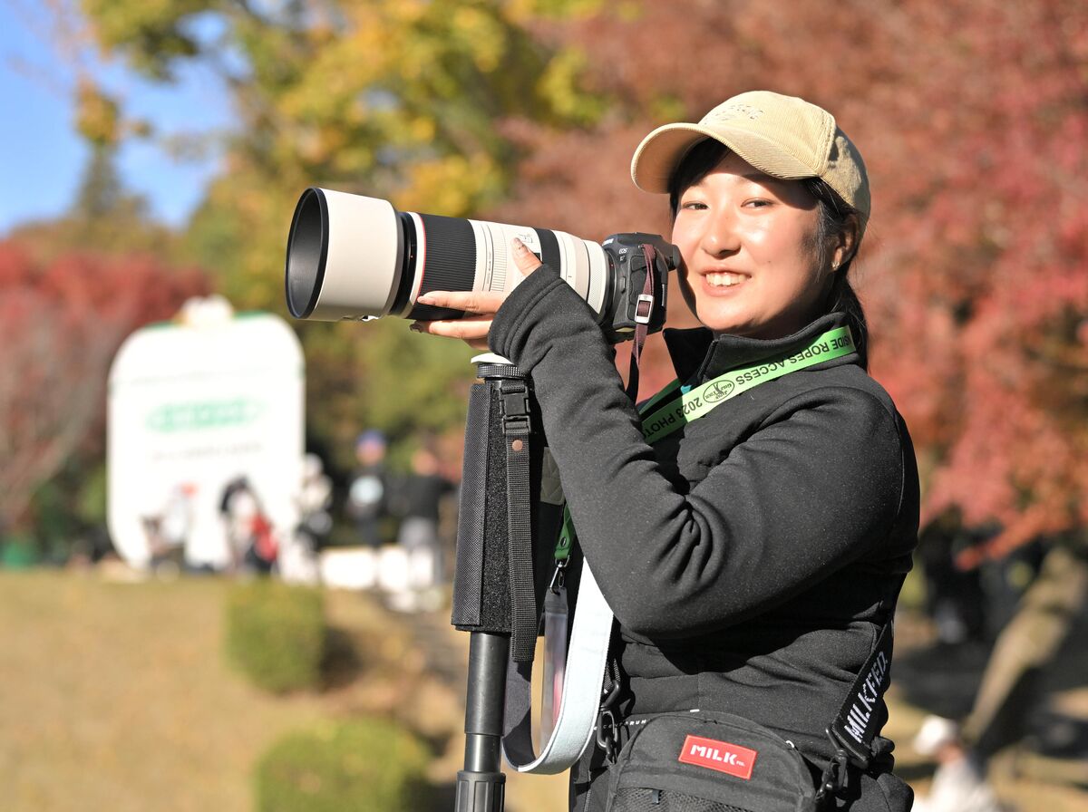 紅葉の１８番で自前のカメラを構える女子プロゴルファーの阿部未悠。写真が趣味の彼女はGDOの企画でカメラマンに挑戦した（カメラ・今西　淳）